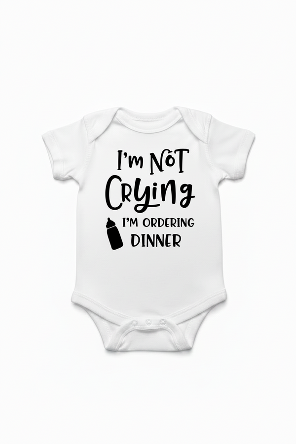 White baby onesie with text 'I'm not crying, I'm ordering dinner' on a white background