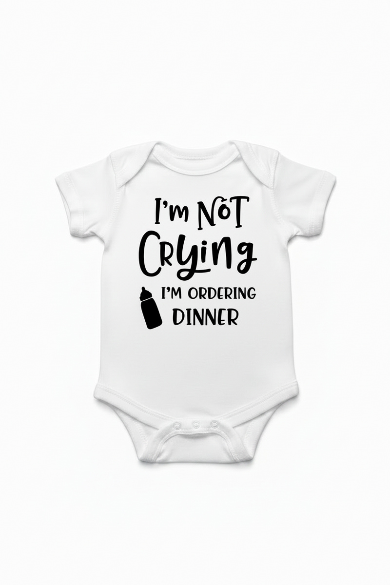 White baby onesie with text 'I'm not crying, I'm ordering dinner' on a white background
