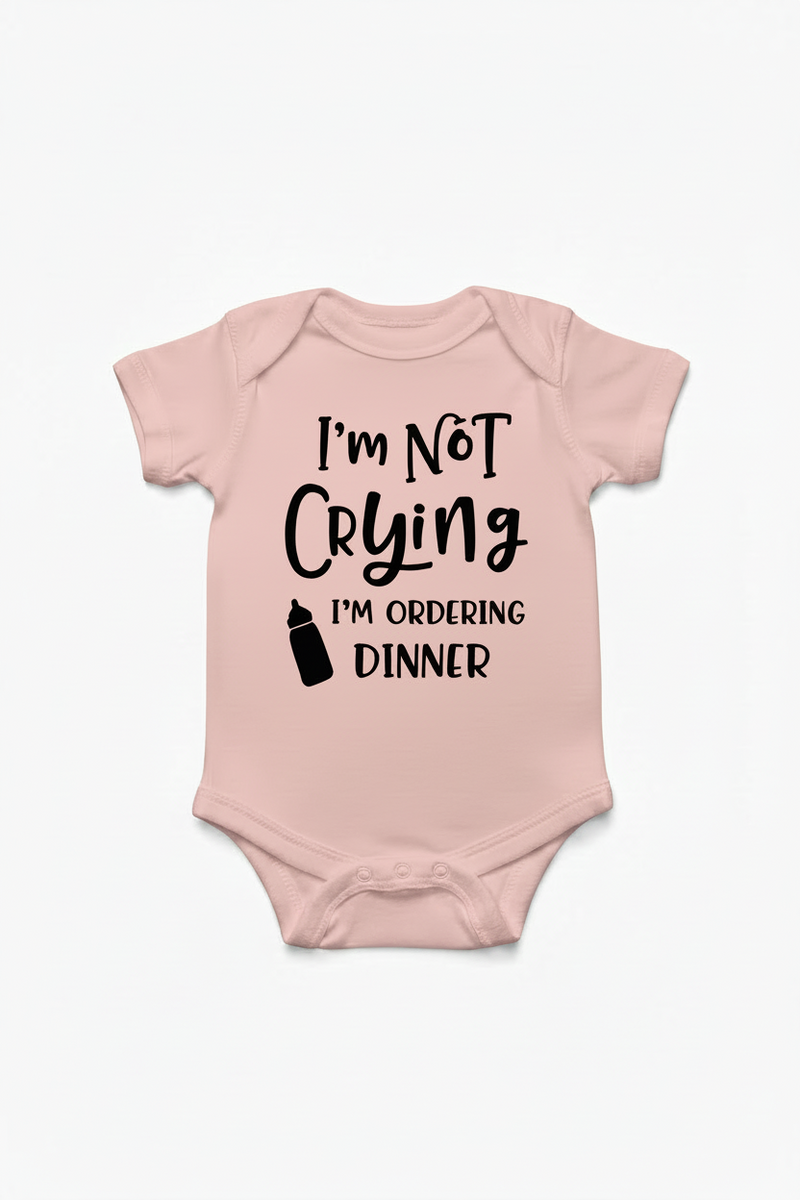 Light pink color baby onesie with text 'I'm Not Crying I'm Ordering Dinner' on a white background