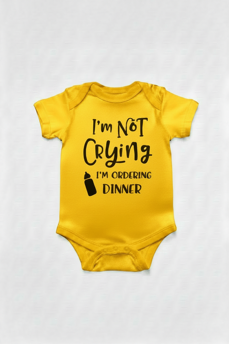 Gold color baby onesie with text 'I'm Not Crying I'm Ordering Dinner' on a white background
